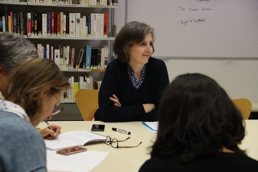 Aline Pacvoň assise autour d’une table lors d’un atelier d’écriture, avec des participantes.